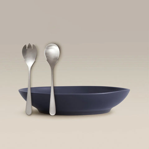 Silver fork and spoon beside a navy bowl on a beige background.