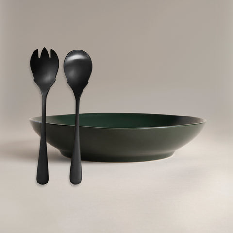 All Is Served Set matte black utensils leaning in front of a dark green bowl on a neutral background